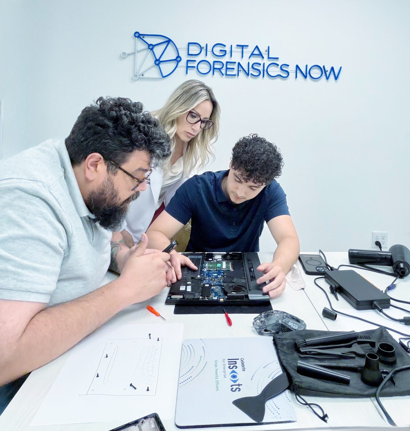Digital Forensics Now team examining device internals at a lab bench